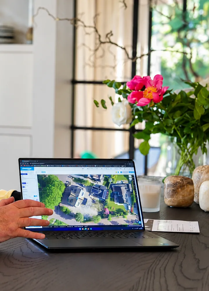 Adviseur van SolarFast laat op een laptop het dak van een klant zien, met bloemen op tafel