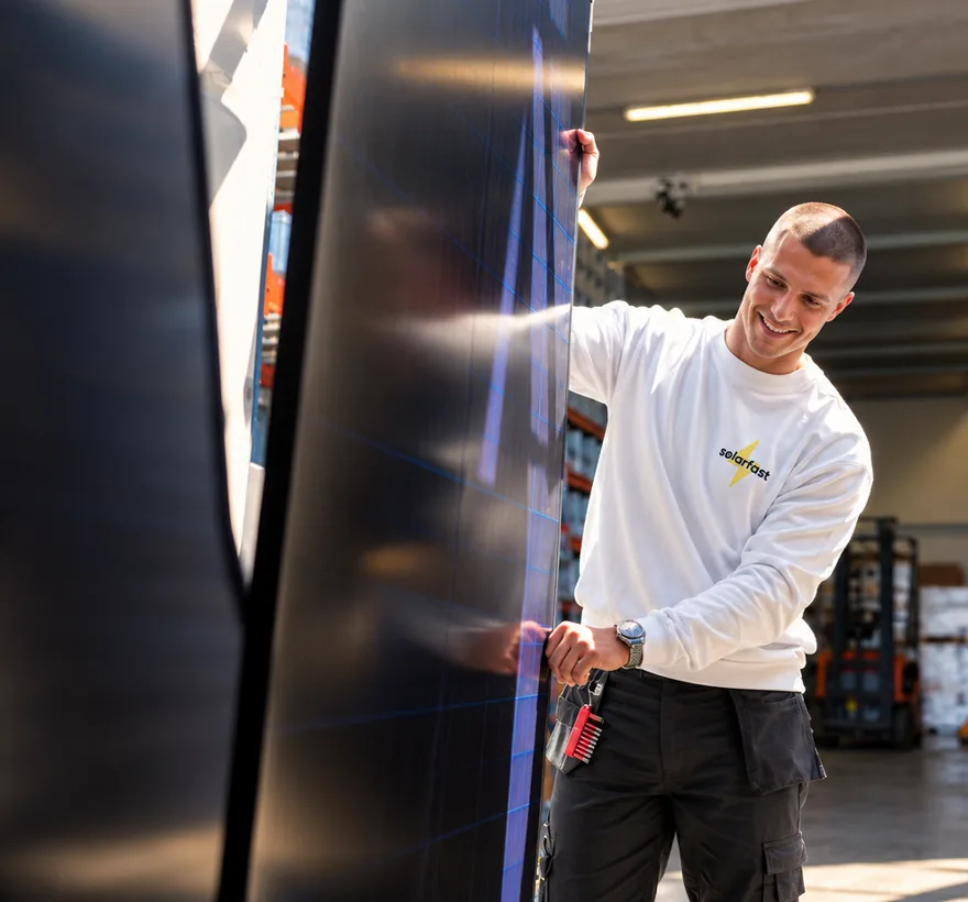 Monteur van SolarFast met een zonnepaneel in het magazijn